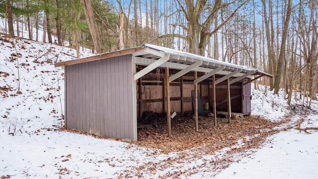 snow covered structure featuring an outdoor structure and a pole building