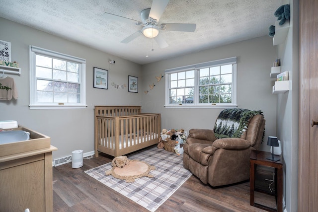 1005 Glenn Ave, Washington Court House, OH 43160 - bedroom featuring wood finished floors, a ceiling fan, a textured ceiling, baseboards, and a crib
