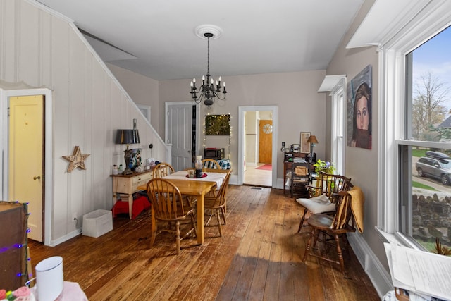 dining room featuring stairway, hardwood / wood-style floors, and an inviting chandelier