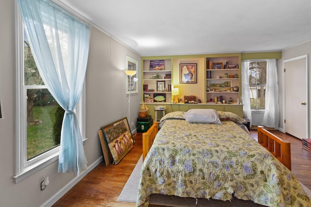 bedroom featuring baseboards, wood finished floors, and multiple windows