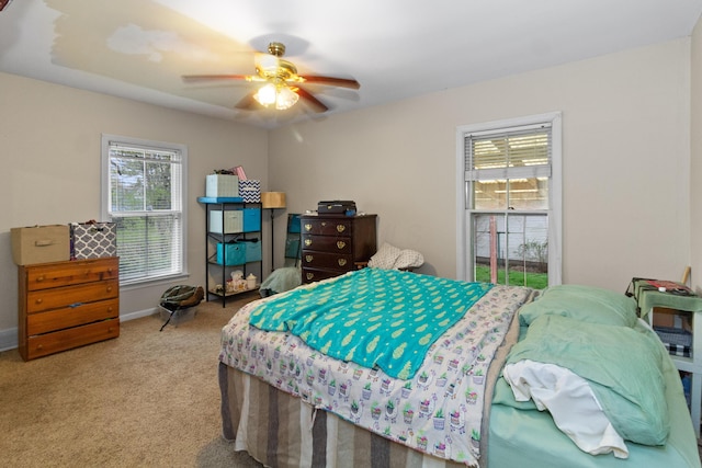 carpeted bedroom featuring a ceiling fan, baseboards, and multiple windows