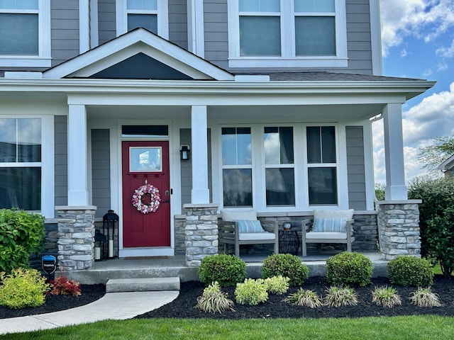 doorway to property with a porch and stone siding