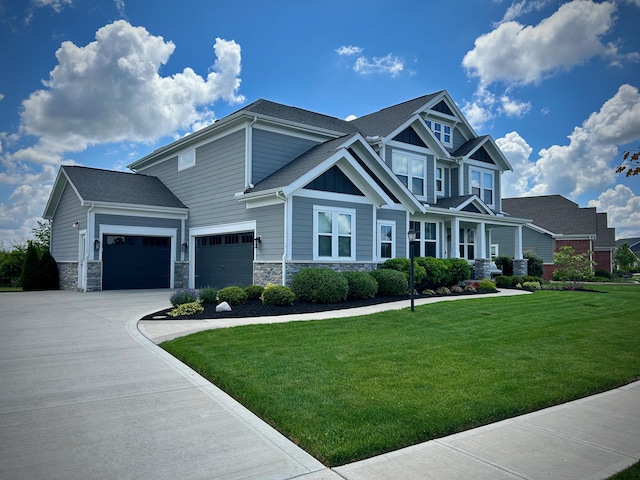 craftsman-style house featuring an attached garage, stone siding, a front lawn, and concrete driveway