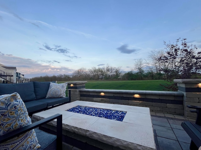patio terrace at dusk featuring a yard and an outdoor living space with a fire pit