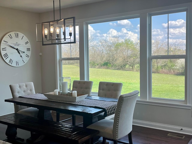 dining room with a healthy amount of sunlight, dark wood-style flooring, baseboards, visible vents, and an inviting chandelier