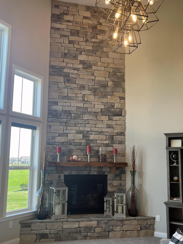 details with a stone fireplace, baseboards, and a notable chandelier