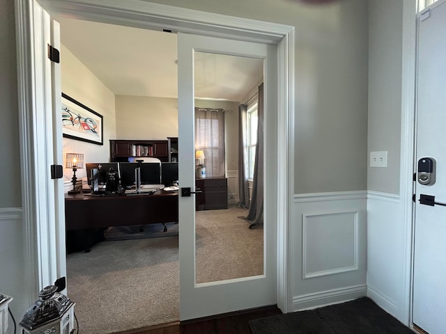 carpeted home office with a wainscoted wall