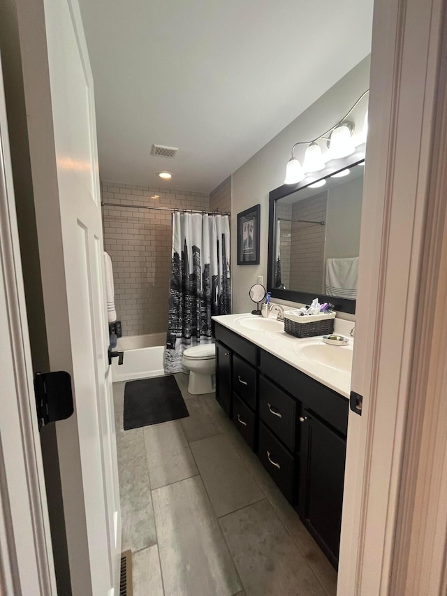 full bath featuring visible vents, a sink, double vanity, and toilet