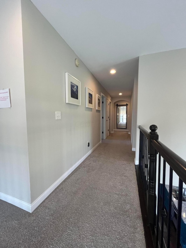 hall featuring recessed lighting, dark carpet, baseboards, and an upstairs landing