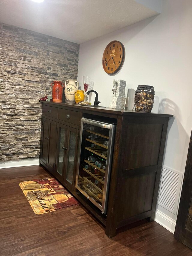 bar with wine cooler, visible vents, dark wood-style floors, and a bar