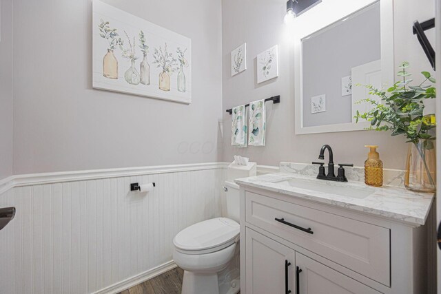 bathroom with wood finished floors, a wainscoted wall, vanity, and toilet