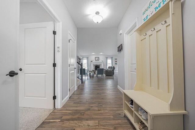 mudroom with dark wood-type flooring, a fireplace, and baseboards