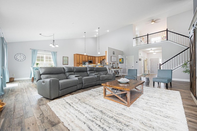 living room with high vaulted ceiling, stairway, wood finished floors, ceiling fan, and baseboards