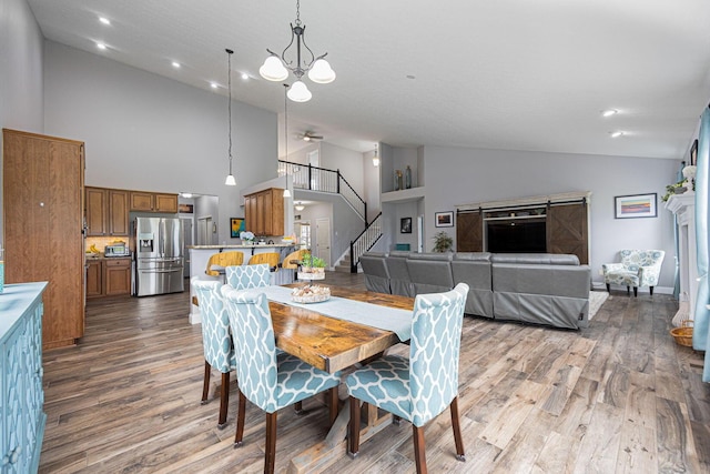 dining area with recessed lighting, light wood finished floors, high vaulted ceiling, stairs, and a notable chandelier