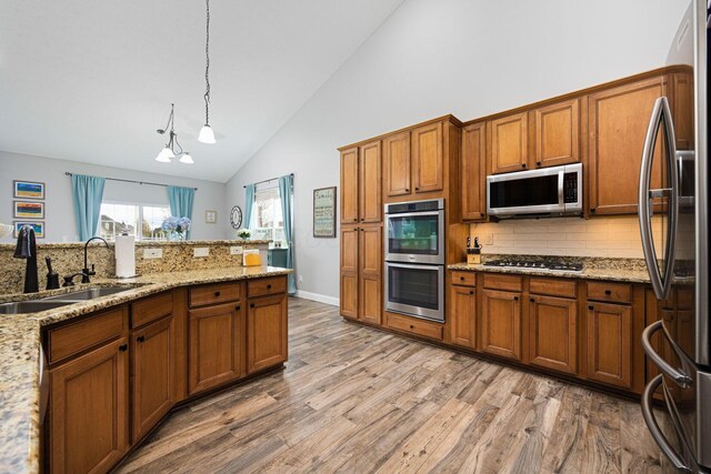 kitchen with brown cabinets, tasteful backsplash, stainless steel appliances, and a sink