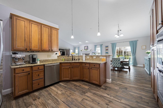 kitchen with brown cabinets, a peninsula, appliances with stainless steel finishes, and a sink
