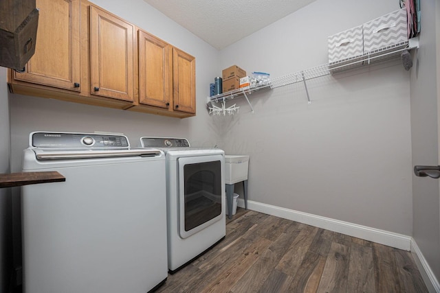 washroom featuring cabinet space, baseboards, dark wood-style flooring, and washer and clothes dryer