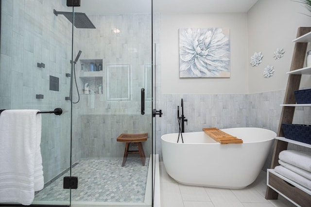bathroom featuring a shower stall, tile patterned flooring, a freestanding bath, tile walls, and wainscoting
