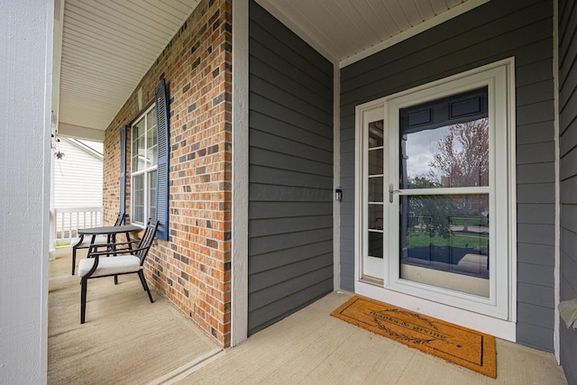 doorway to property with brick siding and covered porch