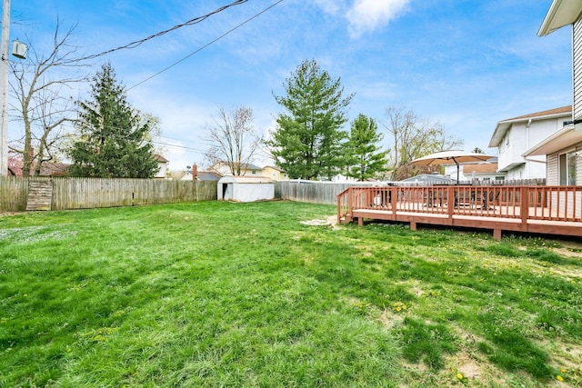 view of yard featuring a fenced backyard, an outbuilding, a deck, and a storage unit