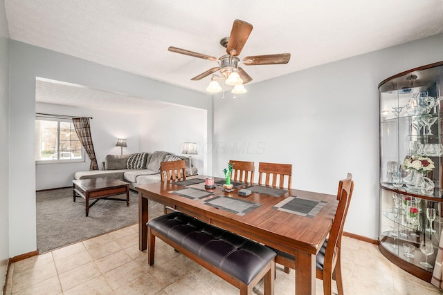 dining area featuring light colored carpet, baseboards, a ceiling fan, and light tile patterned floors