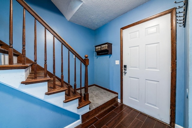entrance foyer featuring wood finish floors, stairs, a textured ceiling, and baseboards