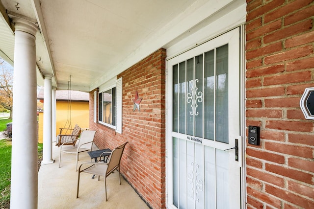 doorway to property with brick siding and a porch