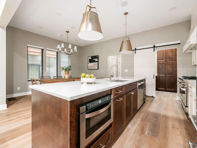 496 W 1st Ave, Columbus, OH 43201 - kitchen with a sink, appliances with stainless steel finishes, an island with sink, and light wood-style flooring