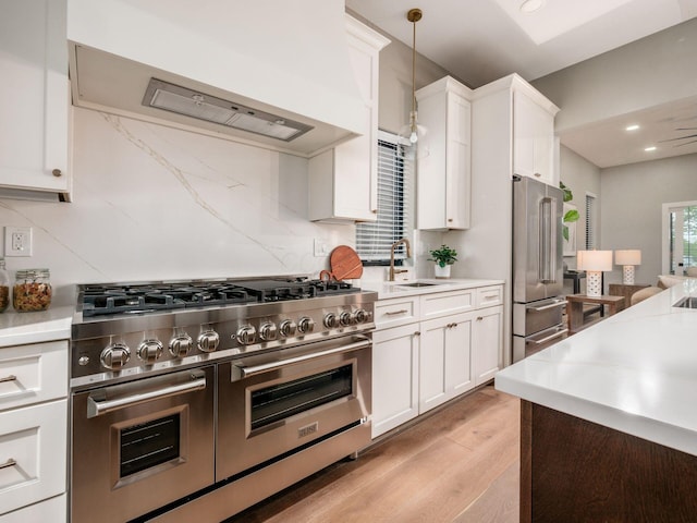 496 W 1st Ave, Columbus, OH 43201 - kitchen with premium appliances, a sink, light wood-style floors, range hood, and light countertops
