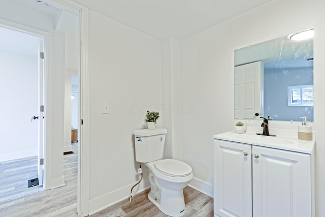 bathroom with baseboards, wood finished floors, toilet, and vanity
