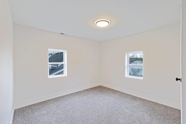 carpeted empty room featuring visible vents and baseboards