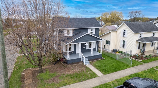 traditional-style home with roof with shingles, central AC unit, a gate, covered porch, and a front yard