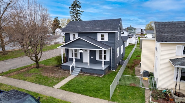 view of front facade with a gate, fence, a front lawn, covered porch, and roof with shingles