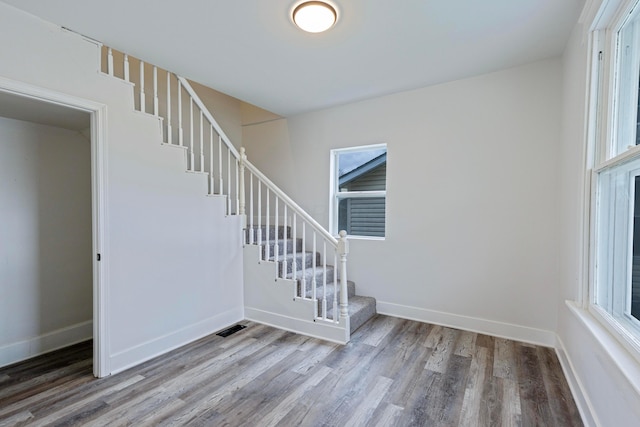 stairway with baseboards, wood finished floors, and visible vents