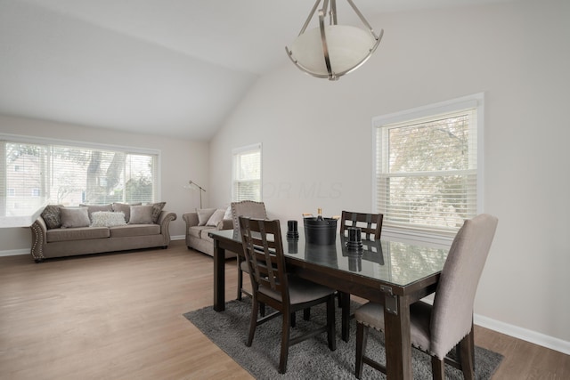 dining room with vaulted ceiling, baseboards, and light wood-style floors