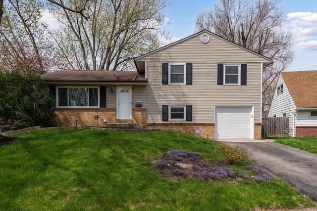 tri-level home with brick siding, an attached garage, a front yard, and aphalt driveway