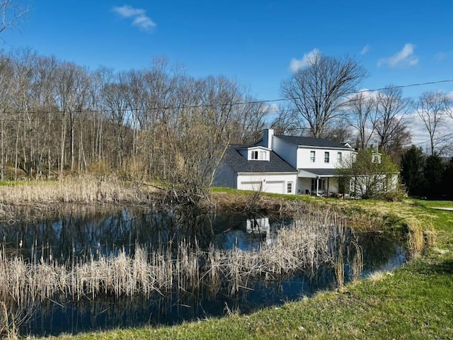 exterior space featuring an attached garage, a chimney, and a water view
