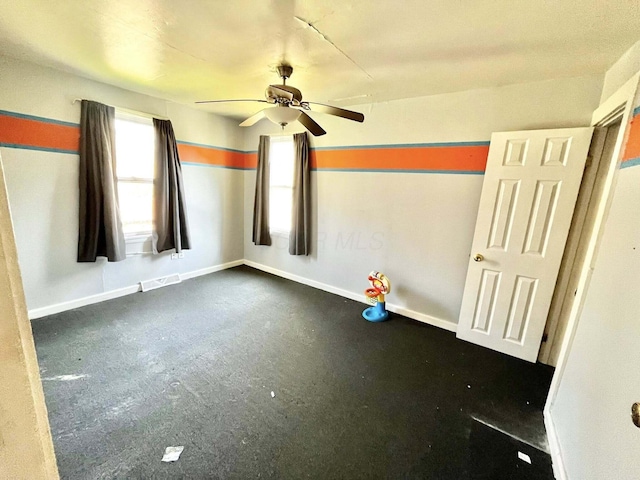 empty room with baseboards, a ceiling fan, and visible vents