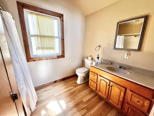 full bath with toilet, vaulted ceiling, baseboards, wood finished floors, and vanity