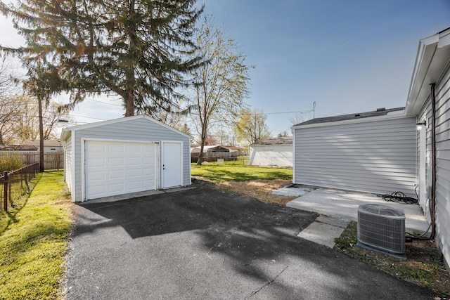 detached garage with central AC unit, fence, and aphalt driveway
