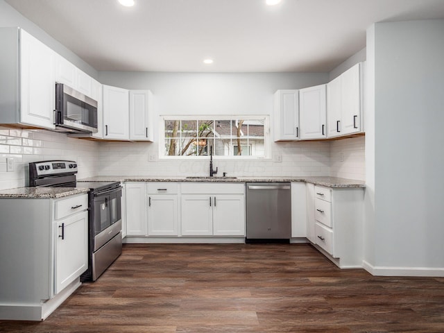 kitchen featuring light stone counters, appliances with stainless steel finishes, a sink, and white cabinetry