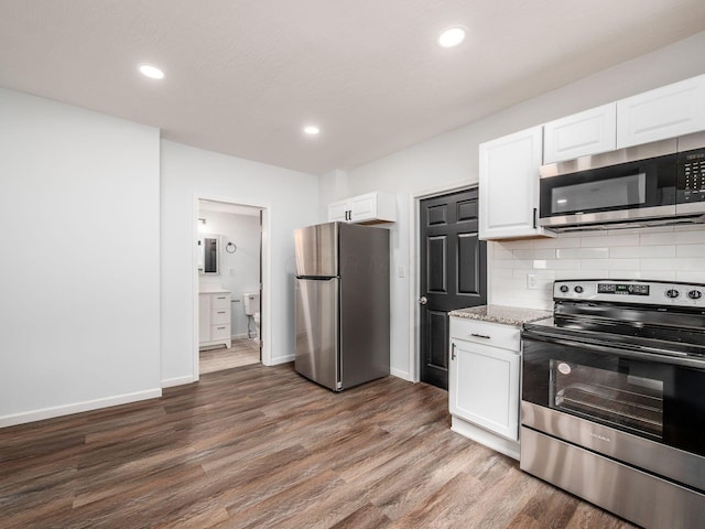kitchen featuring white cabinets, backsplash, wood finished floors, baseboards, and appliances with stainless steel finishes