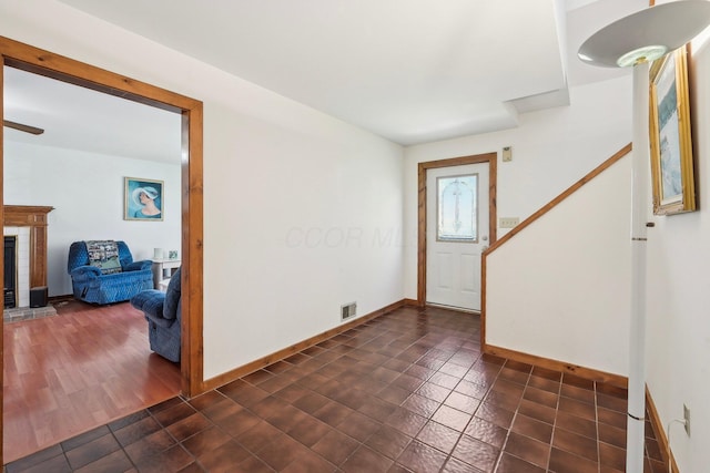 foyer featuring a fireplace, visible vents, baseboards, and dark tile patterned flooring