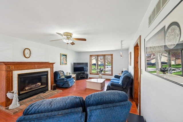 living room featuring a fireplace, wood finished floors, visible vents, and a ceiling fan
