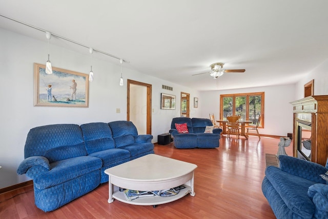living area with visible vents, a ceiling fan, wood finished floors, and track lighting
