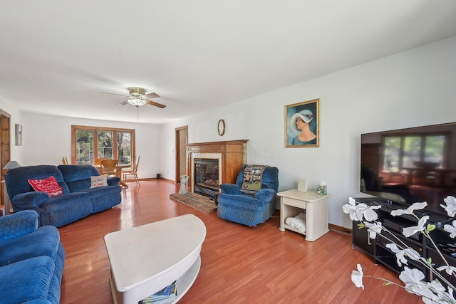 living room with a high end fireplace, wood finished floors, and ceiling fan