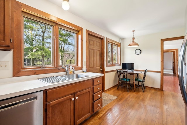 kitchen with light countertops, dishwasher, brown cabinetry, and a sink