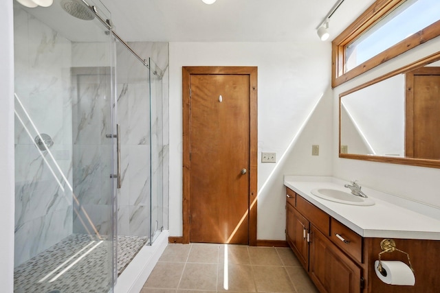 bathroom with tile patterned flooring, baseboards, vanity, and a marble finish shower