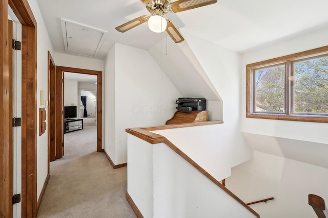 hallway with attic access, baseboards, light colored carpet, and an upstairs landing