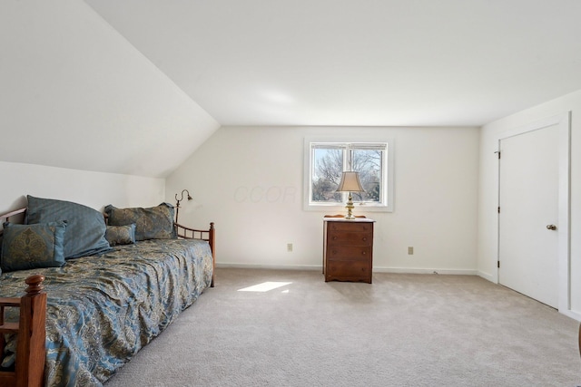 bedroom with light colored carpet, lofted ceiling, and baseboards